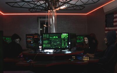 Team of hackers with Guy Fawkes masks coding in a dark room with computers.