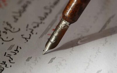 An intimate view of a vintage fountain pen poised over handwritten Arabic text.