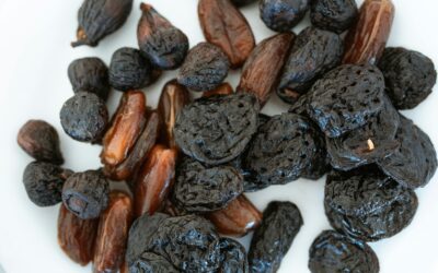 Close-up of assorted dried fruits, including prunes and dates, on a white surface.